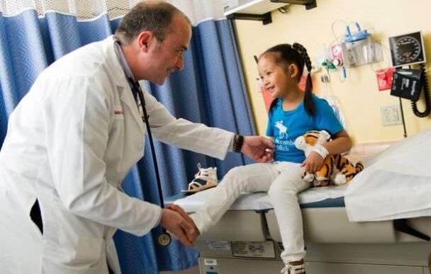 The doctor examines a child with hip joint disease